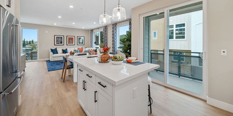 Photo of the inside of a Fusion Apartment. In the photo can be seen a kitchen, kitchen island, and the living room.