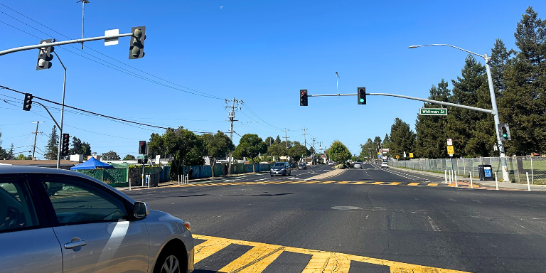 Photo of a car at at traffic signal on Tennnyson Road and Whitman Street. 