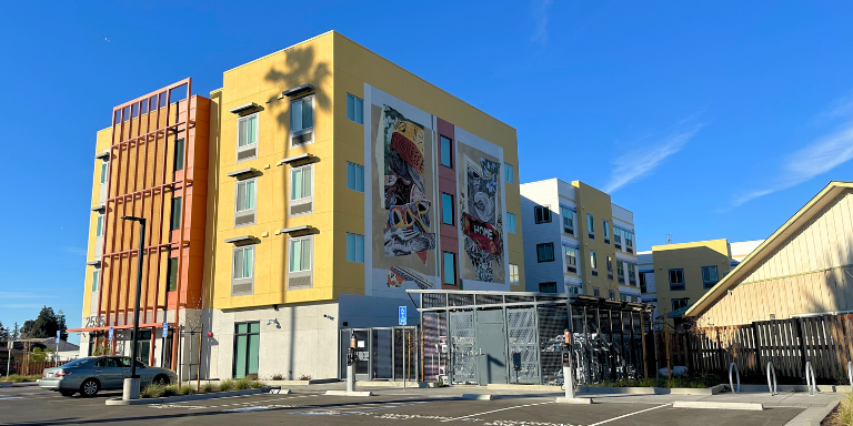 Orange and yellow apartment building with a mural on the side.