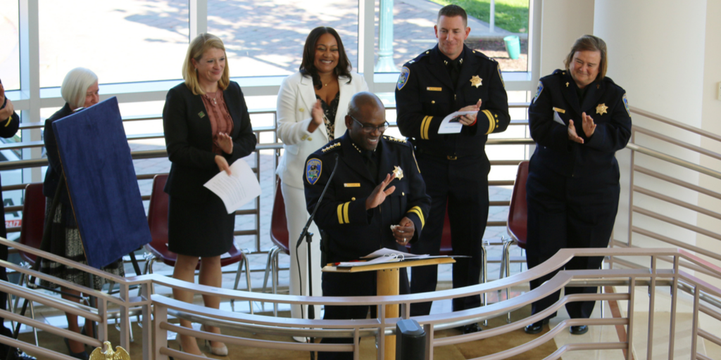 Chief Chaplin smiling and in front of a podium during his swearing in ceremony